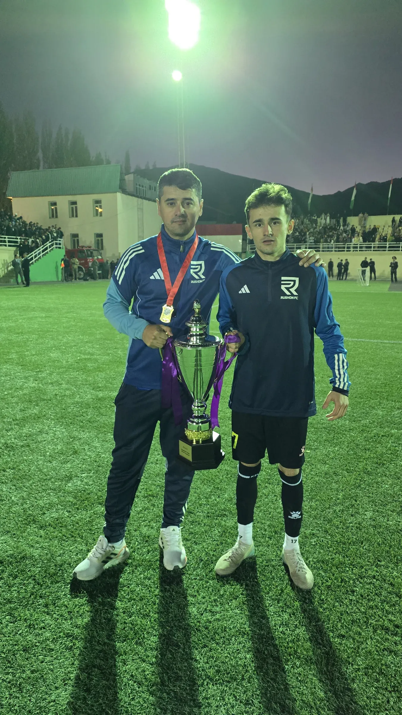 Двое игроков ФК «Рушан» с кубком на поле